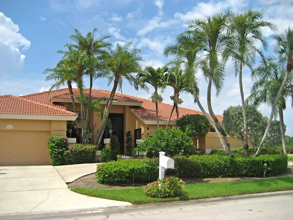 Large upscale house with many palm trees.