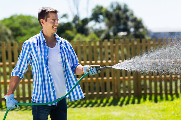 cheerful man watering home garden
