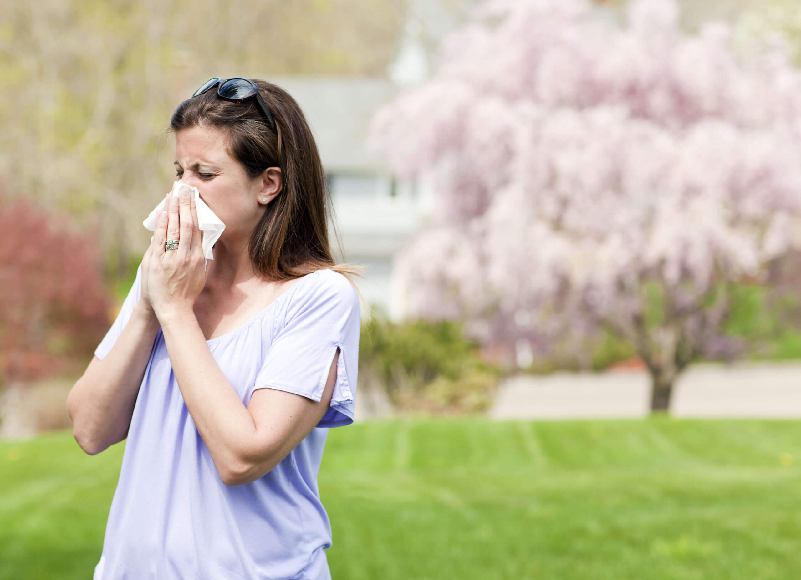 Woman outside blowing nose with a tissue