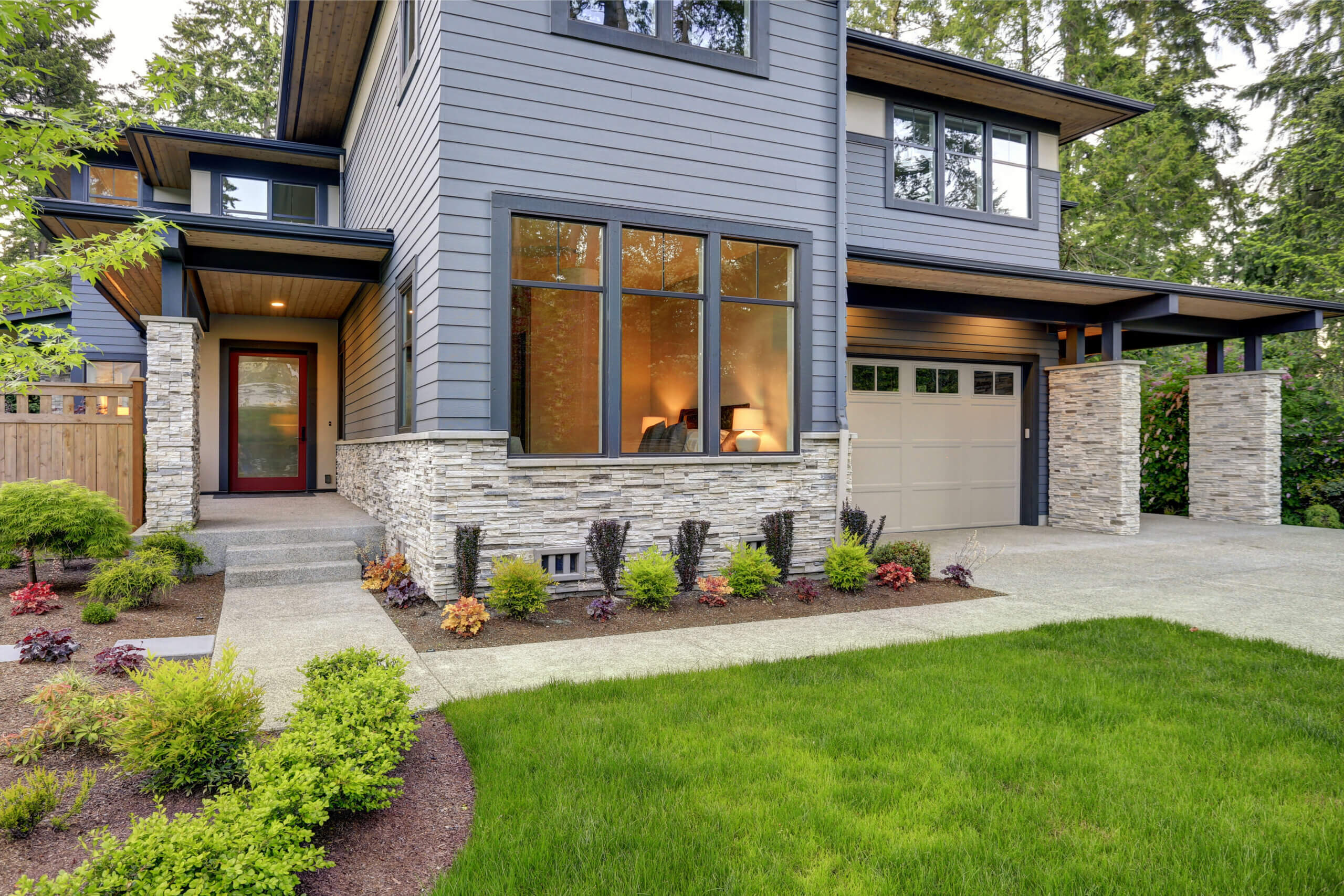 Luxurious new home with curb appeal. Trendy grey two-story exterior in Bellevue with large picture windows, stone foundation veneer, covered porch and concrete pathway. Northwest, USA